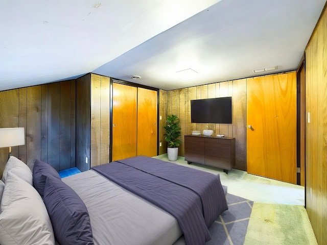 bedroom featuring light carpet, visible vents, and wooden walls