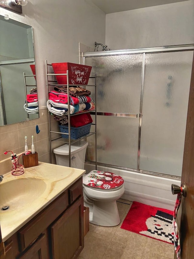 full bathroom featuring vanity, tile patterned floors, combined bath / shower with glass door, decorative backsplash, and toilet