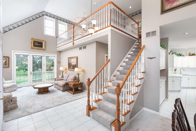 stairway featuring tile patterned floors, a towering ceiling, sink, and french doors