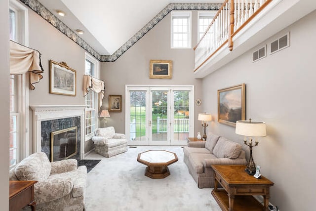 living room featuring carpet, plenty of natural light, a fireplace, and a high ceiling