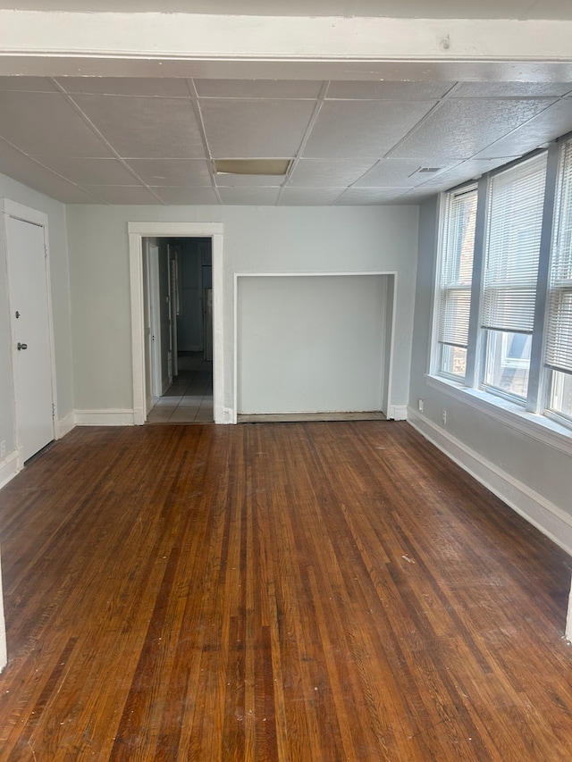 unfurnished room featuring a drop ceiling and dark wood-type flooring