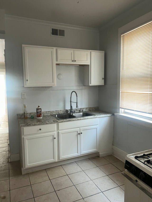 kitchen with white cabinets, light tile patterned floors, crown molding, and sink