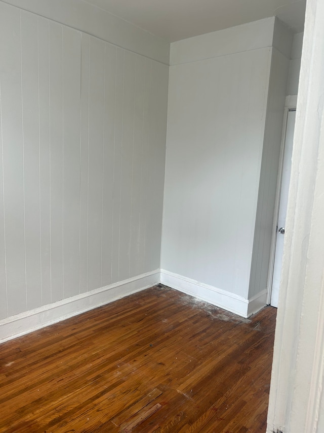 spare room featuring dark hardwood / wood-style floors and wooden walls