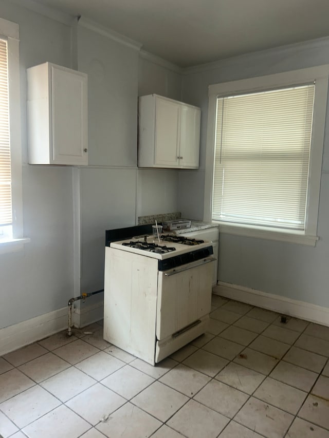 kitchen with gas range gas stove, crown molding, white cabinets, and light tile patterned floors