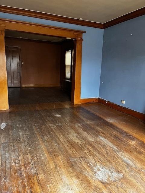 empty room with dark hardwood / wood-style floors and ornamental molding