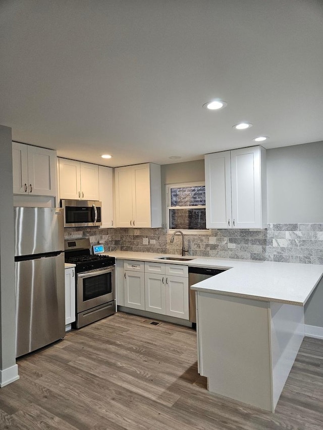 kitchen with sink, white cabinets, stainless steel appliances, and light wood-type flooring