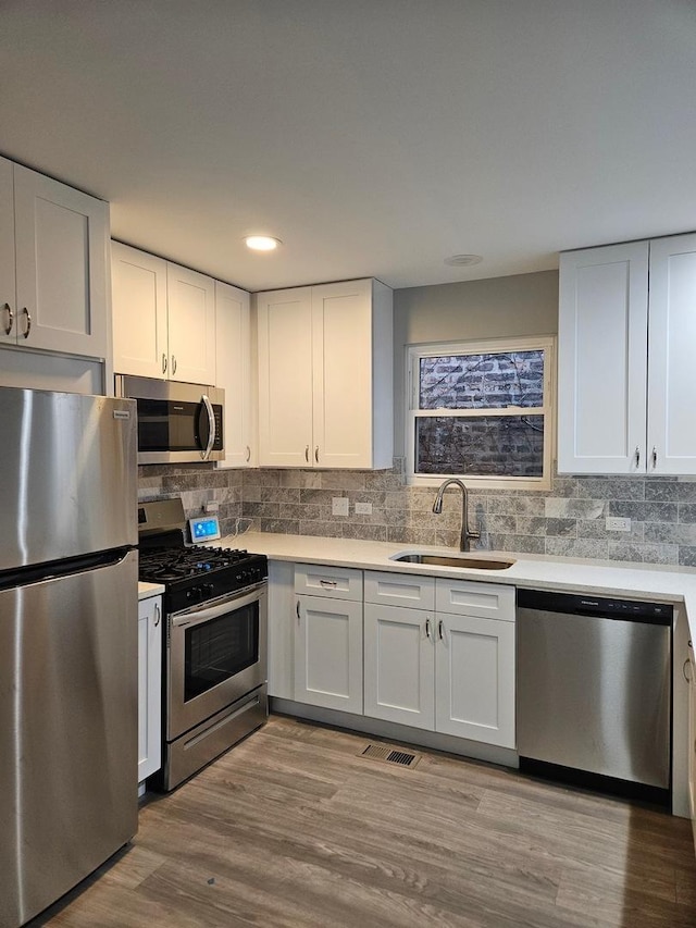 kitchen featuring light hardwood / wood-style floors, sink, white cabinetry, and stainless steel appliances