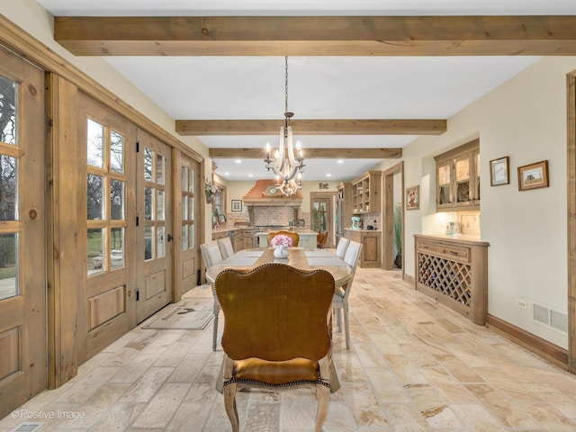 dining area featuring a healthy amount of sunlight, beam ceiling, and an inviting chandelier