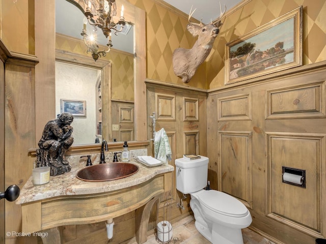 bathroom with sink, ornamental molding, a notable chandelier, and toilet