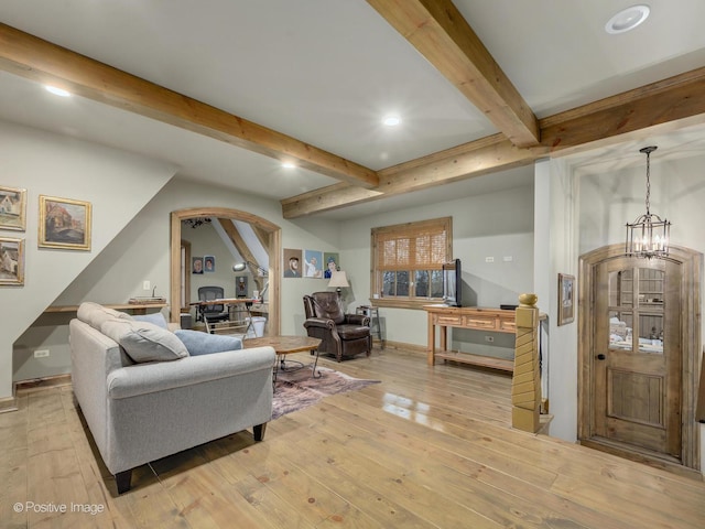 living room featuring beamed ceiling, light hardwood / wood-style floors, and a chandelier