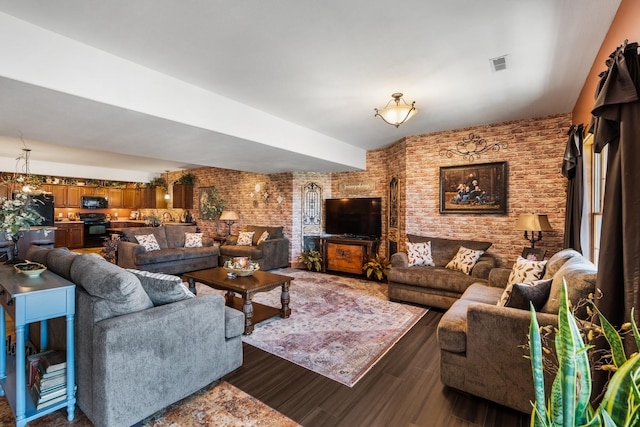 living area featuring brick wall, dark wood-type flooring, and visible vents