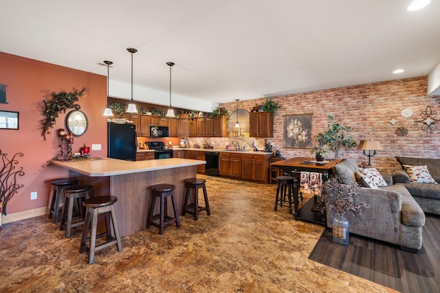 kitchen featuring brown cabinets, a kitchen breakfast bar, a peninsula, light countertops, and black appliances