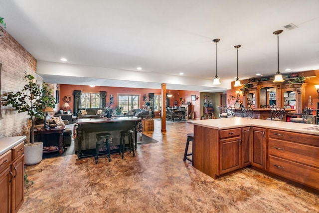 kitchen featuring open floor plan, light countertops, a breakfast bar, and decorative columns