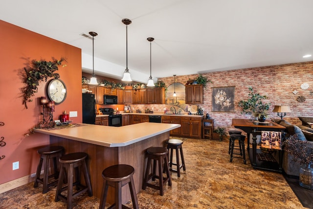 kitchen featuring a kitchen bar, light countertops, a peninsula, and black appliances