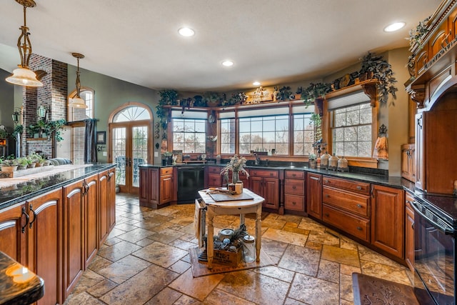 kitchen with dark countertops, black appliances, stone tile floors, and pendant lighting