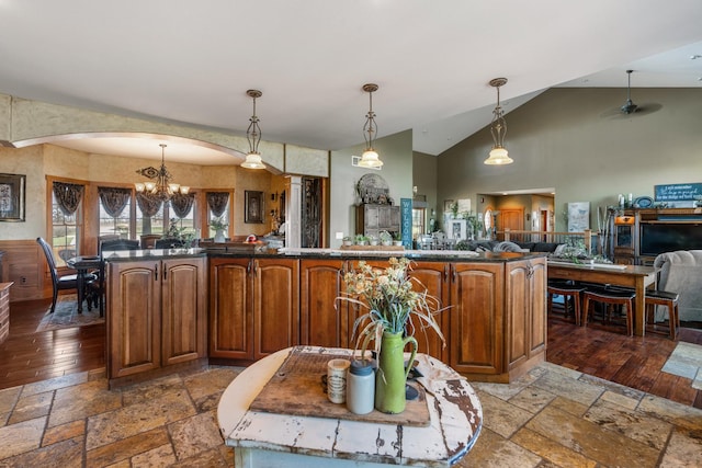 kitchen with dark countertops, open floor plan, decorative light fixtures, and stone tile floors