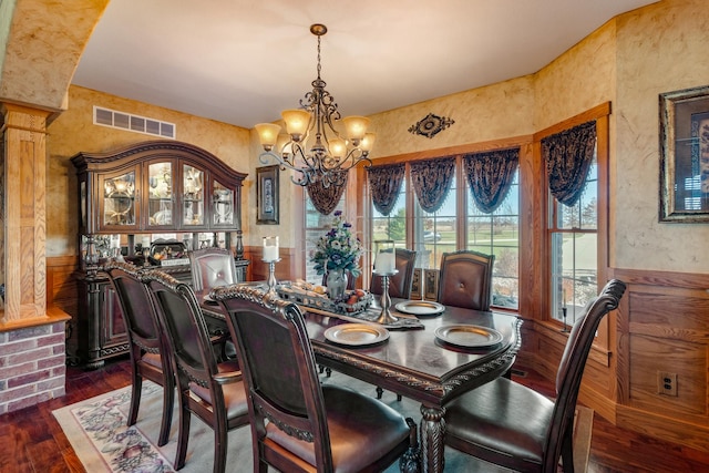 dining area with visible vents, a textured wall, wainscoting, dark wood-style floors, and a notable chandelier