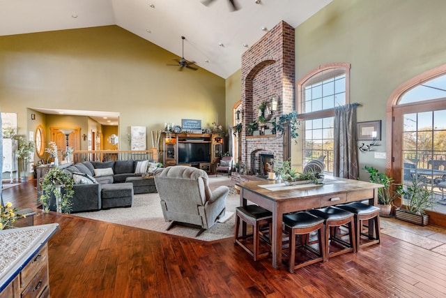 living area with ceiling fan, a fireplace, high vaulted ceiling, and hardwood / wood-style floors