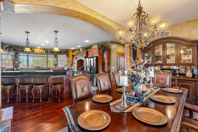 dining space with dark wood-style floors, arched walkways, a notable chandelier, and recessed lighting