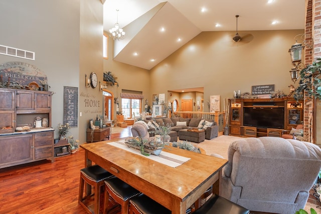 dining space featuring high vaulted ceiling, visible vents, wood finished floors, and ceiling fan with notable chandelier