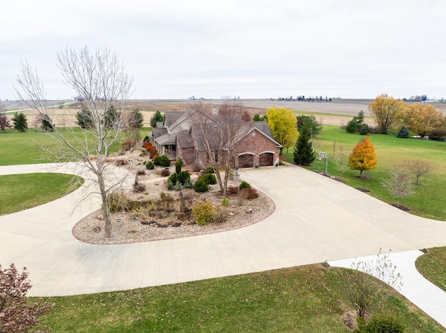 exterior space with an attached garage, driveway, a rural view, and a front yard