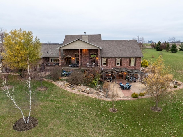 rear view of house featuring brick siding, a patio, and a lawn