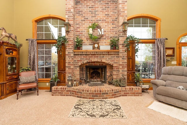 living room featuring a towering ceiling, a brick fireplace, and carpet flooring