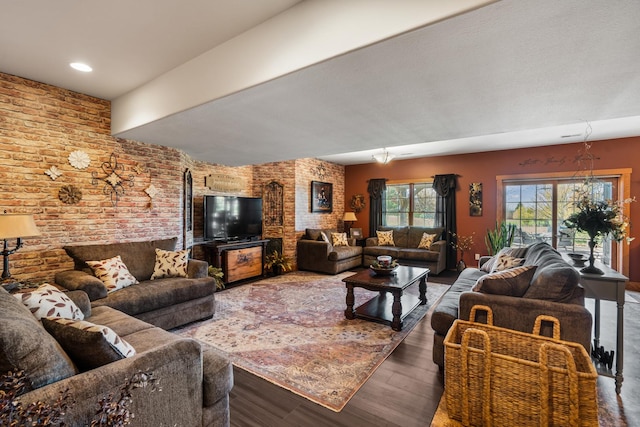 living room featuring brick wall and wood finished floors