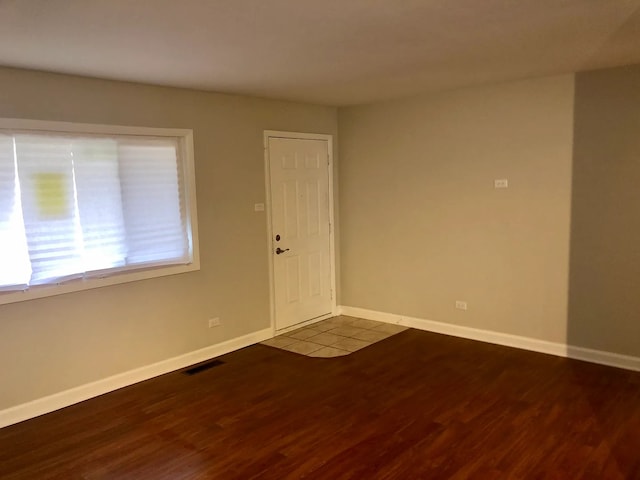 spare room featuring wood finished floors, visible vents, and baseboards