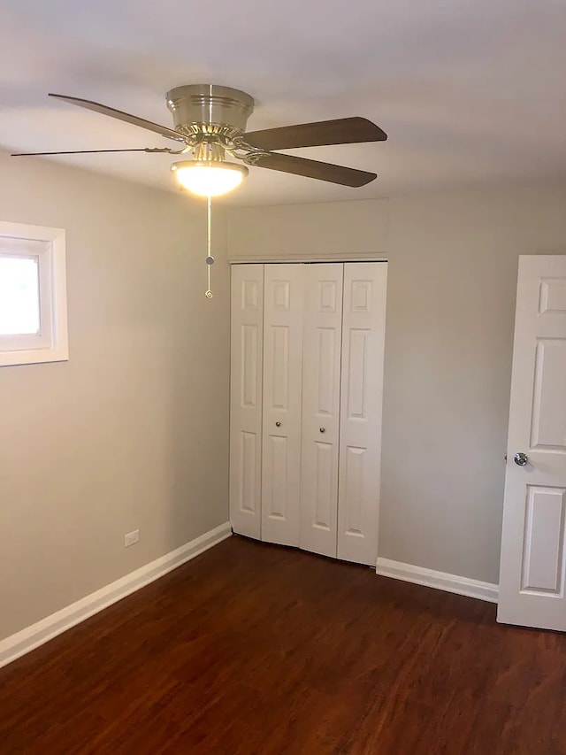 unfurnished bedroom with a ceiling fan, baseboards, dark wood finished floors, and a closet