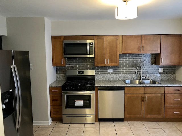 kitchen with backsplash, stainless steel appliances, a sink, and light countertops