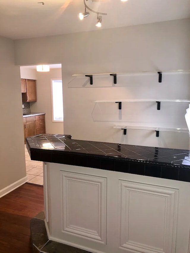 kitchen featuring tile counters, white cabinets, and wood finished floors