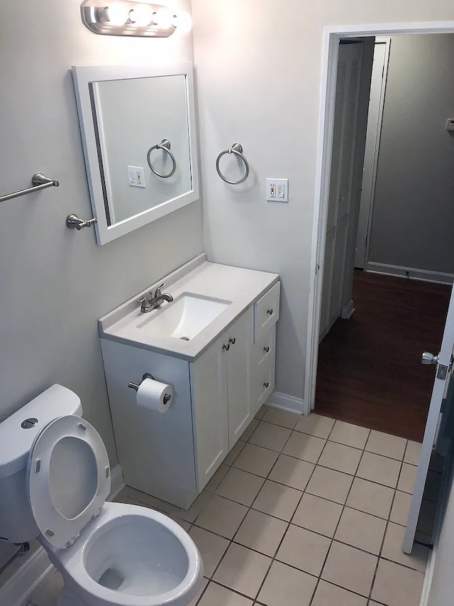 half bath featuring tile patterned flooring, vanity, and toilet