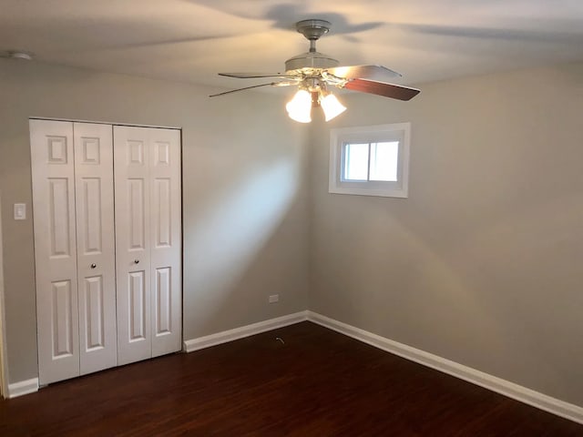 unfurnished bedroom with dark wood-type flooring, a closet, a ceiling fan, and baseboards