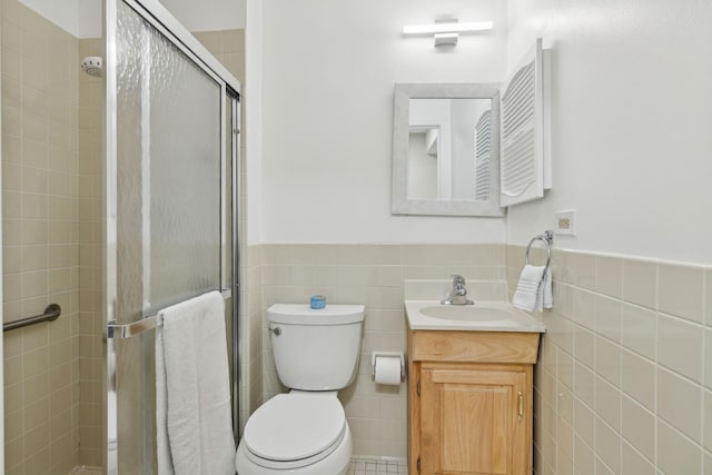 bathroom featuring tile walls, an enclosed shower, vanity, and toilet