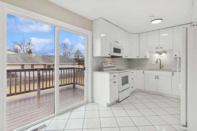 kitchen with sink, white cabinetry, light tile patterned floors, white appliances, and backsplash