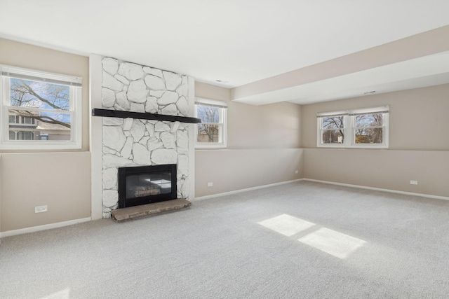 unfurnished living room featuring a stone fireplace and carpet flooring