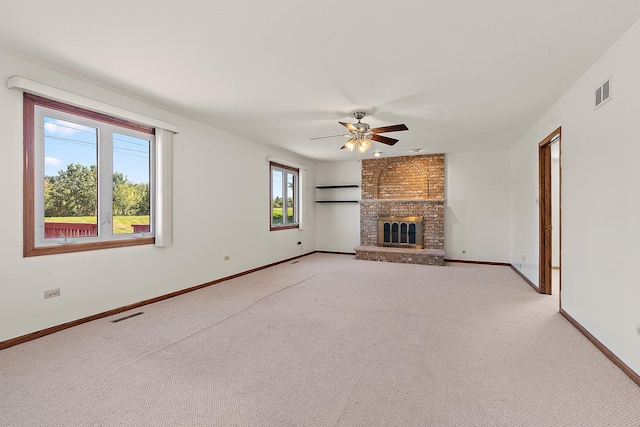 unfurnished living room featuring light carpet, ceiling fan, and a brick fireplace