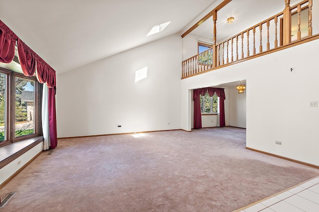 unfurnished living room featuring light carpet, beamed ceiling, a skylight, and a healthy amount of sunlight