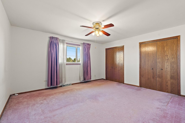 unfurnished bedroom with ceiling fan, carpet floors, and two closets