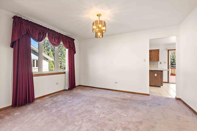 spare room with a notable chandelier and light carpet