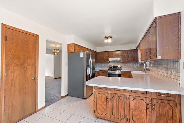 kitchen featuring sink, appliances with stainless steel finishes, tasteful backsplash, light colored carpet, and kitchen peninsula