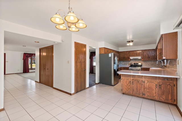 kitchen featuring sink, stainless steel appliances, a notable chandelier, backsplash, and kitchen peninsula