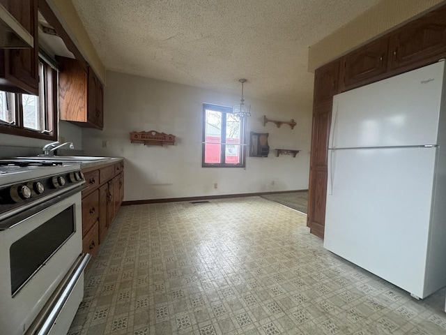 kitchen with pendant lighting, a textured ceiling, a notable chandelier, white fridge, and range