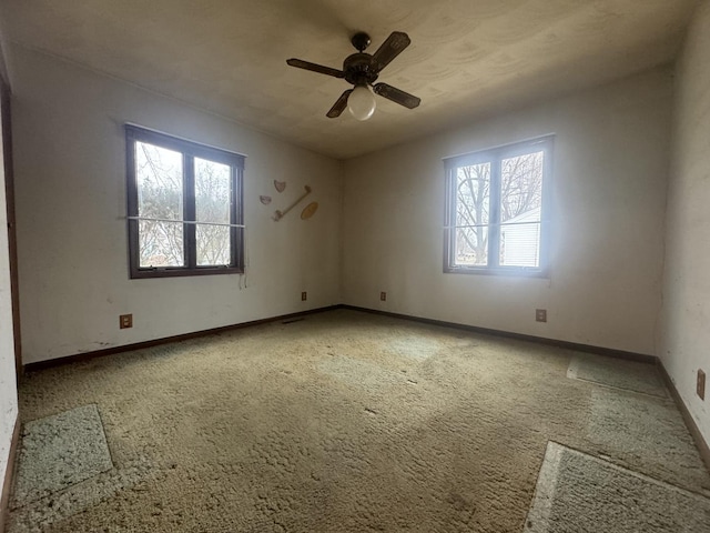 unfurnished room featuring plenty of natural light, ceiling fan, and carpet floors