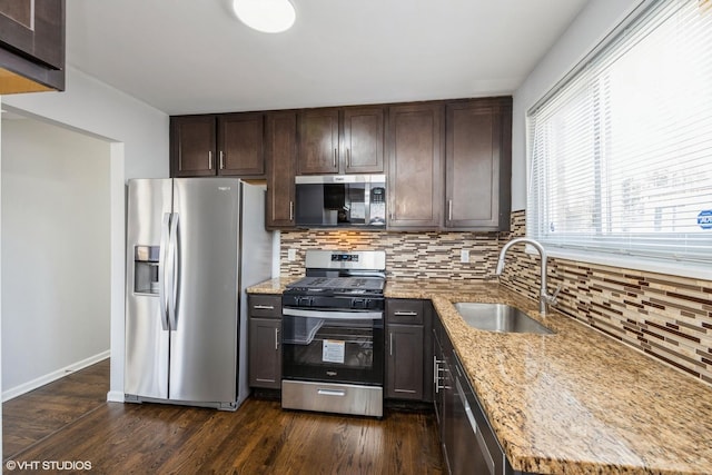 kitchen with light stone counters, sink, stainless steel appliances, and dark wood-type flooring