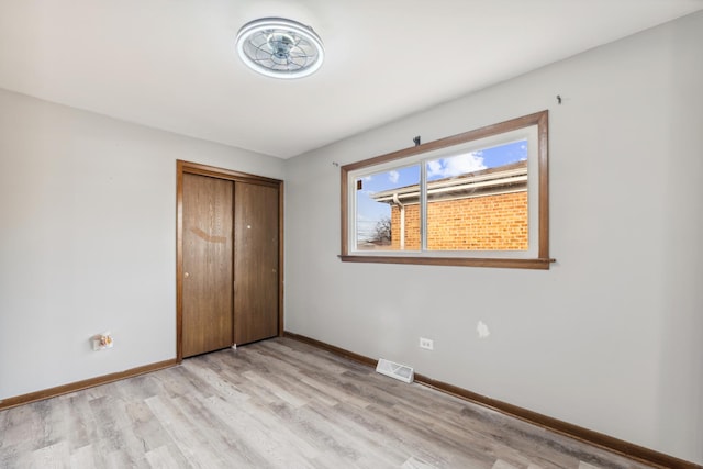 unfurnished bedroom with a closet and light wood-type flooring