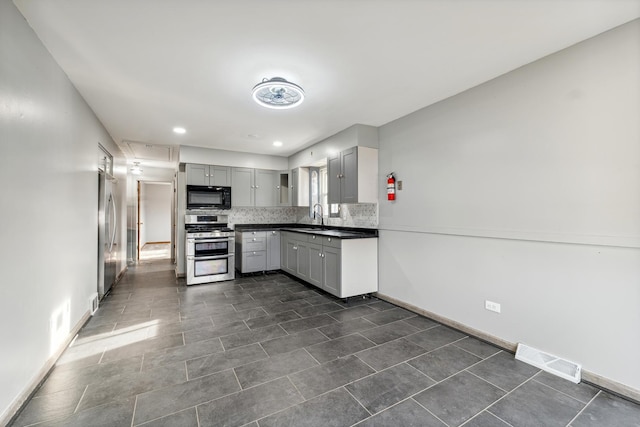 kitchen with gray cabinetry, sink, backsplash, and appliances with stainless steel finishes