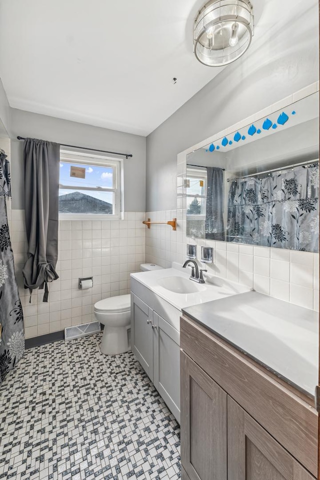 bathroom featuring vanity, toilet, and tile walls