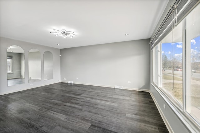 empty room featuring plenty of natural light and dark hardwood / wood-style floors